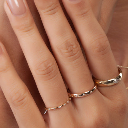 Model wearing minimalist yellow gold diamond wedding band with pavé-set lab diamonds, styled with other rings for a layered bridal look.