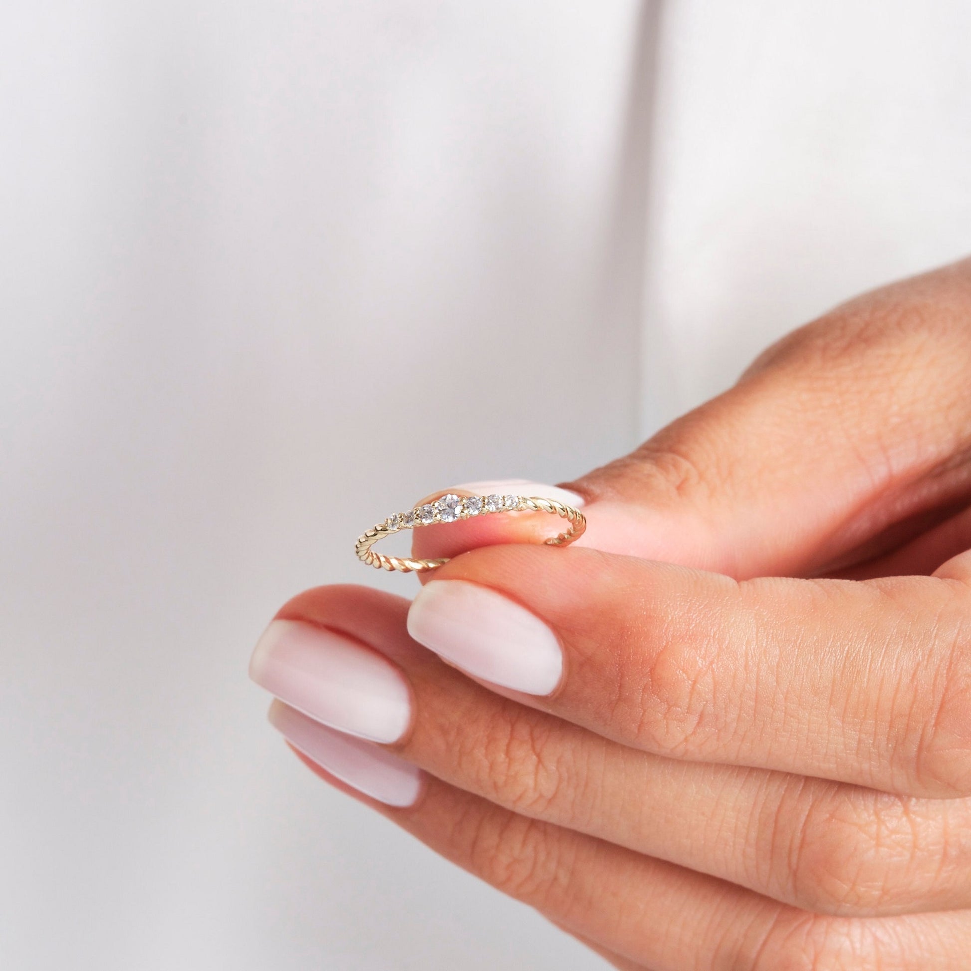 Hand holding the yellow gold Diamond Wedding Ring - Lab Diamonds | Carat Rio, showcasing its fine twisted rope and diamond setting.