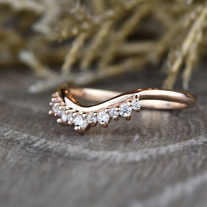 Close-up of rose gold Round Diamond Tiara Ring on wood surface, featuring chevron band and prong-set diamonds.